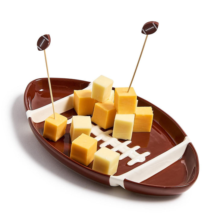 Football-shaped platter with cheese cubes and toothpicks on a white background