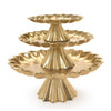 Three gold cake stands with scalloped edges stacked on top of each other on a white background