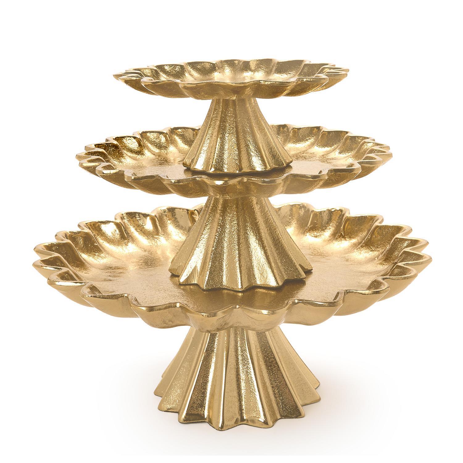 Three gold cake stands with scalloped edges stacked on top of each other on a white background