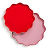 Two scalloped-edge plates, one red and one pink, on a white background.