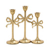 Three gold candle holders with bow designs on a white background