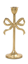 Gold candle holder with bow design on a white background