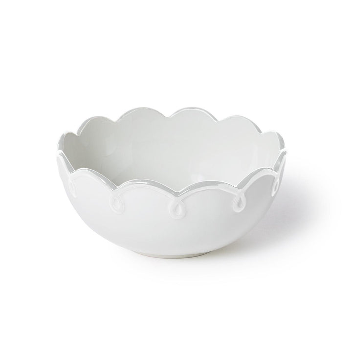 White ceramic bowl with scalloped edge on a white background