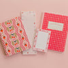 Set of stationery items including notebooks and to-do lists with strawberry and checkered designs on a pink background.