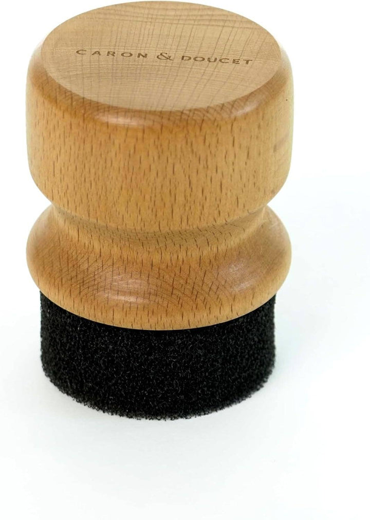 Wooden and black applicator brush with 'Caron & Doucet' branding on a white background