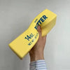 Hand holding a yellow Butter squishy toy against a gray background