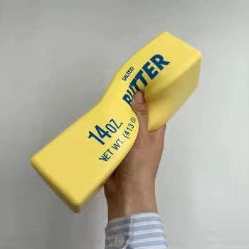 Hand holding a yellow Butter squishy toy against a gray background