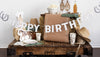 Decorative birthday setup with 'Happy Birthday' banner, hats, and drinks on a wooden table.