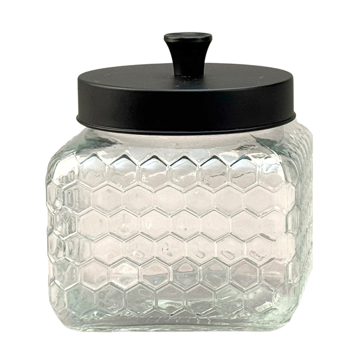 Glass jar with honeycomb pattern and black lid on a white background