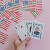 Hand holding playing cards with a pink background