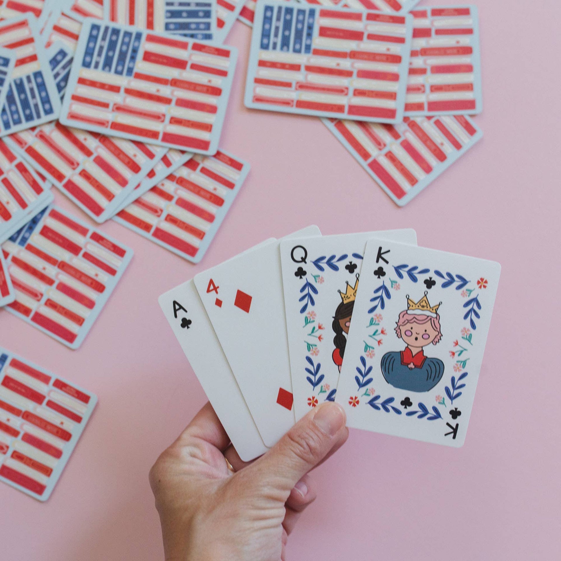 Hand holding playing cards with a pink background