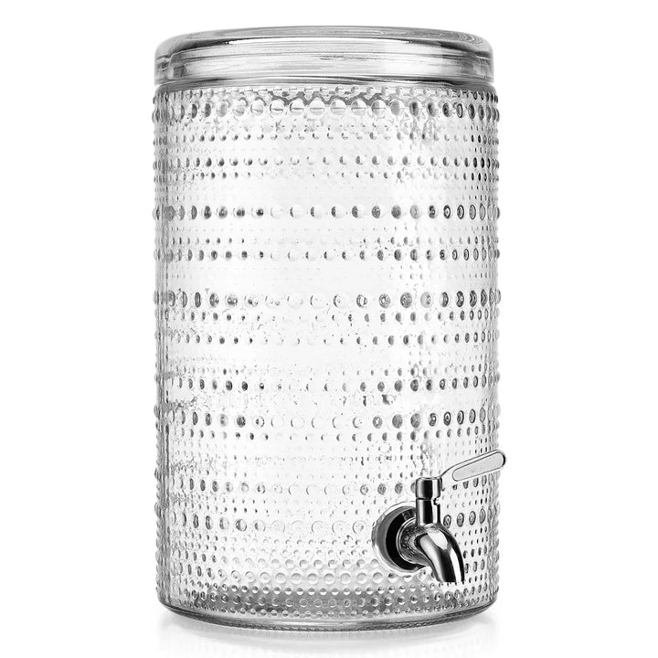 Clear glass drink dispenser with textured surface and metal spigot on a white background