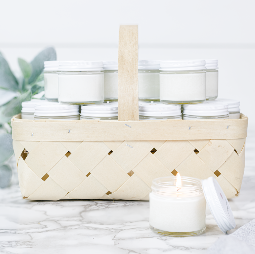 Wicker basket filled with white jars on a marble surface a lighted candle in the foreground