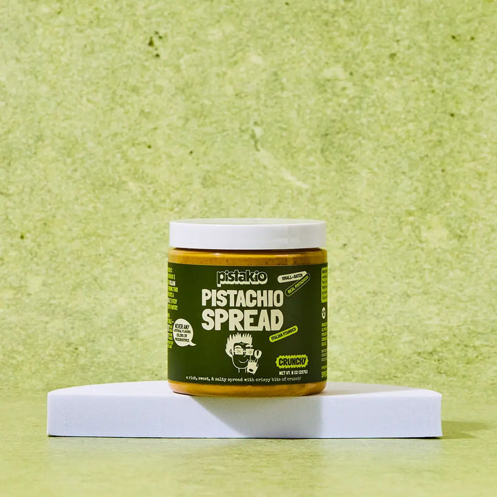 Jar of pistachio spread on a green background