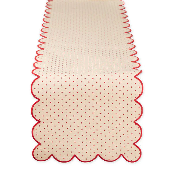 Beige table runner with red scalloped edge and subtle heart pattern on a white background