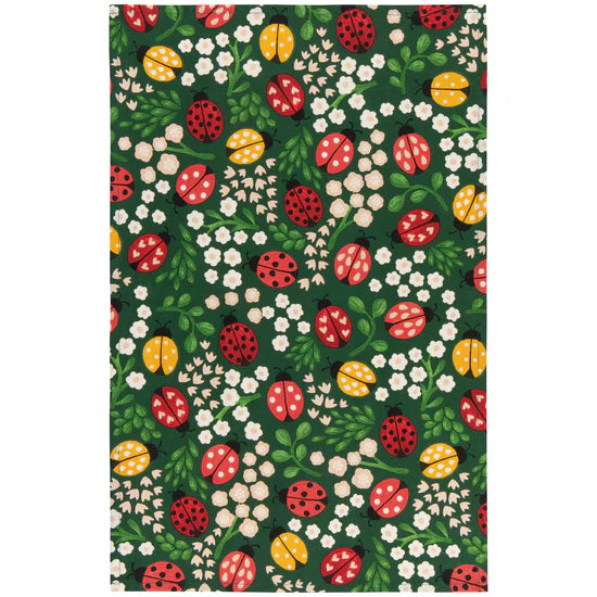 Patterned towel with ladybugs, flowers, and leaves on a green background