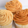 Three cupcakes with orange frosting on a white background