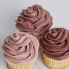 Three cupcakes with rose frosting on a white background