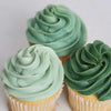 Three cupcakes with green frosting on a white background