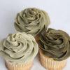 Three cupcakes with tan/brown frosting on a white background