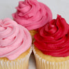 Three cupcakes with pink and red frosting on a white background