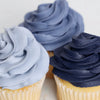 Three cupcakes with blue frosting on a white background