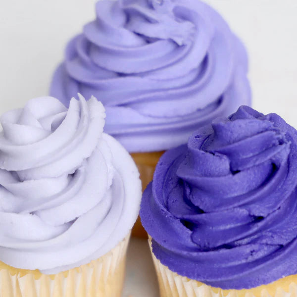 Three cupcakes with purple frosting on a white background