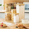 Set of glass storage jars with wooden lids on a kitchen counter.