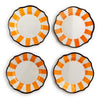 Four scalloped plates with orange and white striped design on a white background