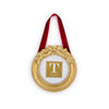 Decorative gold ornament with a red ribbon and holly leaf embellishments on a white background