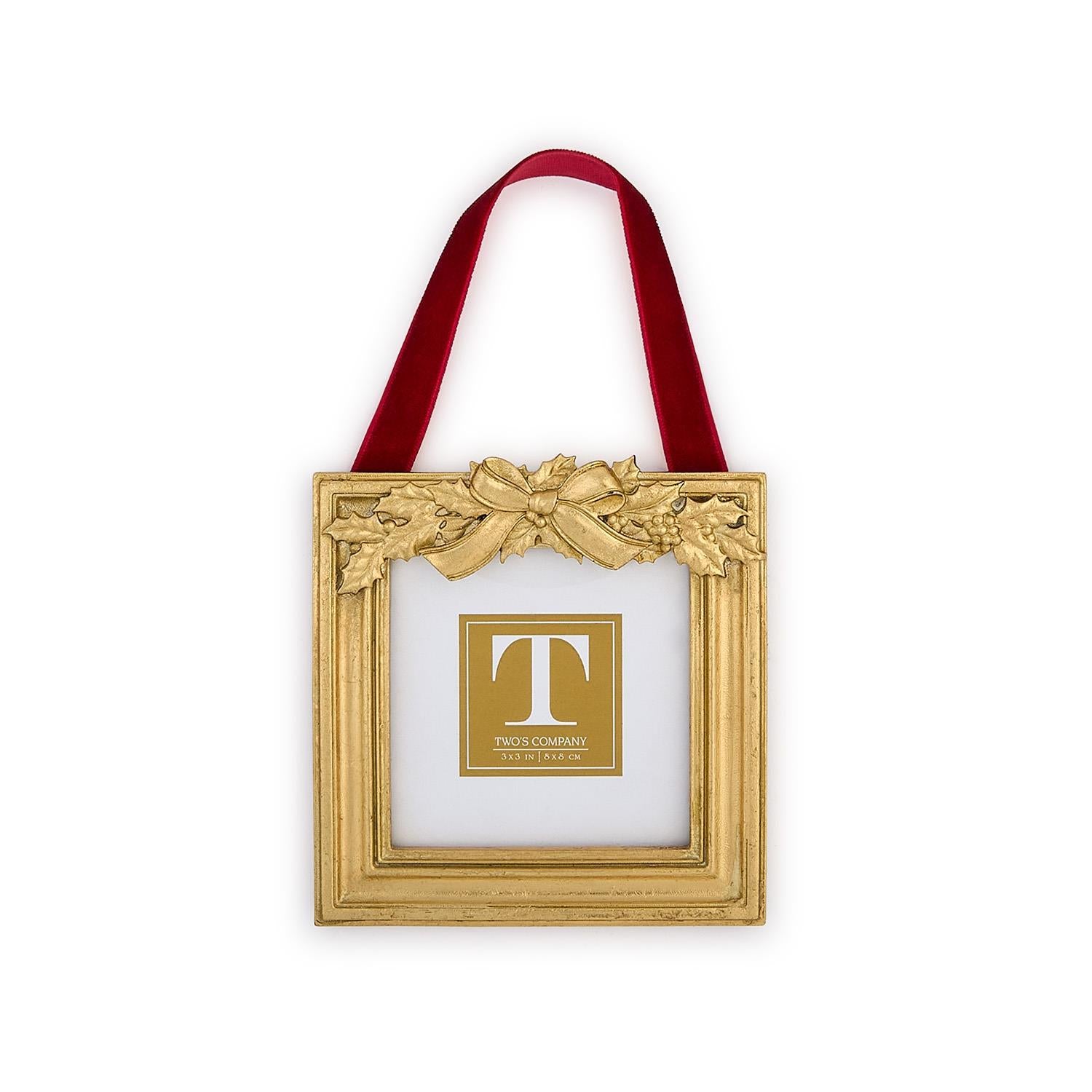 Decorative gold frame with a red ribbon and holly leaf embellishments on a white background