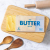 Book titled The Butter book on a wooden cutting board with a rolling pin and wooden spoons.