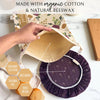 Reusable bread bag and bowl cover with organic cotton and natural beeswax, held by a hand on a white surface.