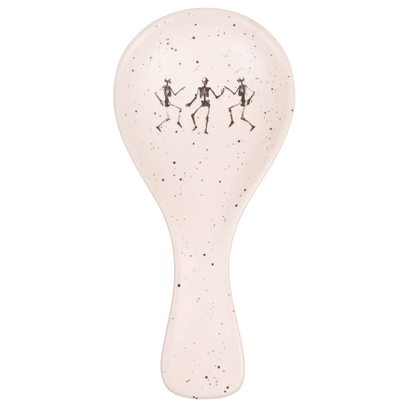 Speckled white spoon rest with black dancing skeletons design on a white background