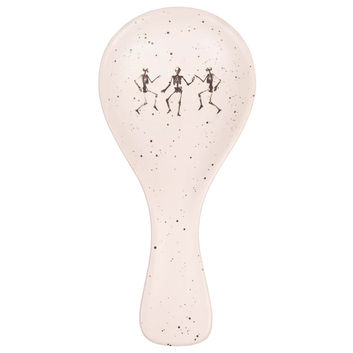 Speckled white spoon rest with black dancing skeletons design on a white background