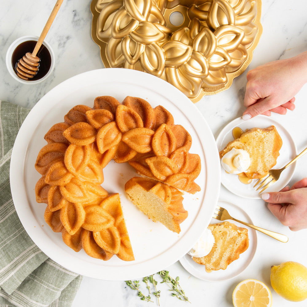 Decorative bundt cake on a white plate with a gold bundt cake pan in the background.