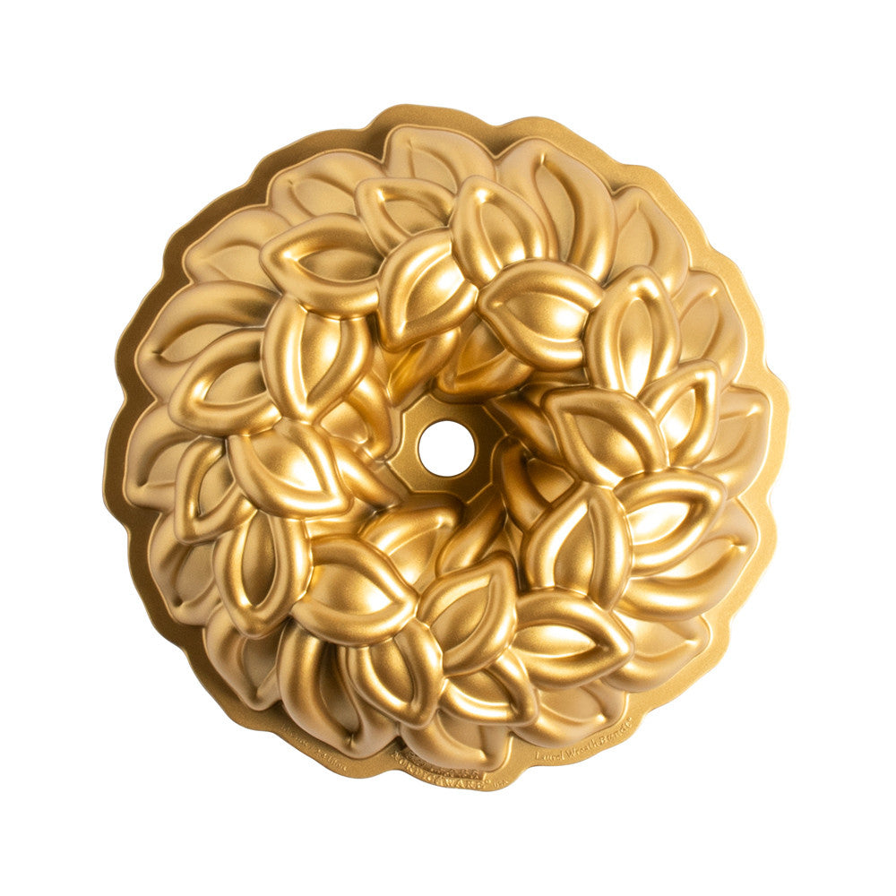 Gold decorative bundt pan with intricate leaf pattern on a white background