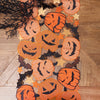 Halloween-themed decorative table runner with pumpkins and bats on a wooden table.