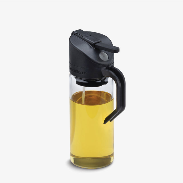 Glass bottle with black cap and handle filled with oil on a white background
