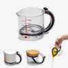 Clear measuring cups with different contents and capacities on a white background.