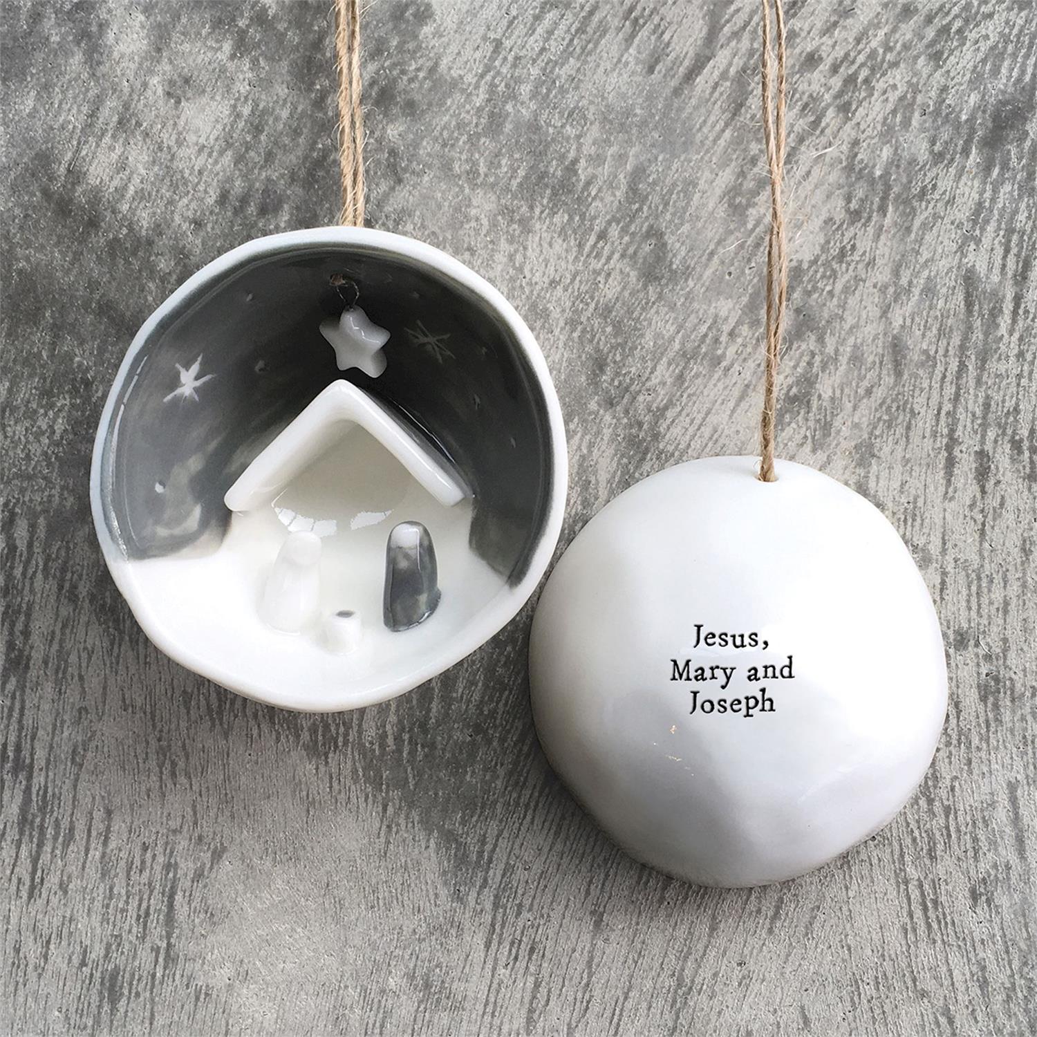 Decorative Christmas ornament with nativity design on one side and text on the other side a wooden surface