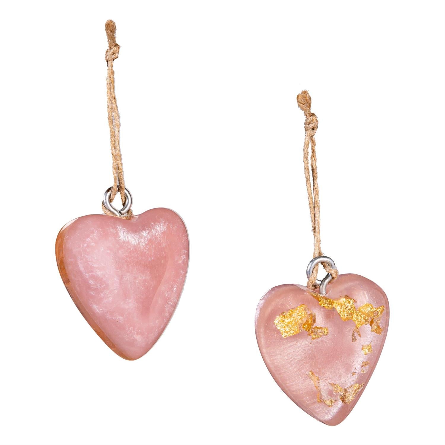 Two pink hanging resin hearts on a white background