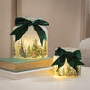 Decorative jars with green bows and forest scene on a neutral background