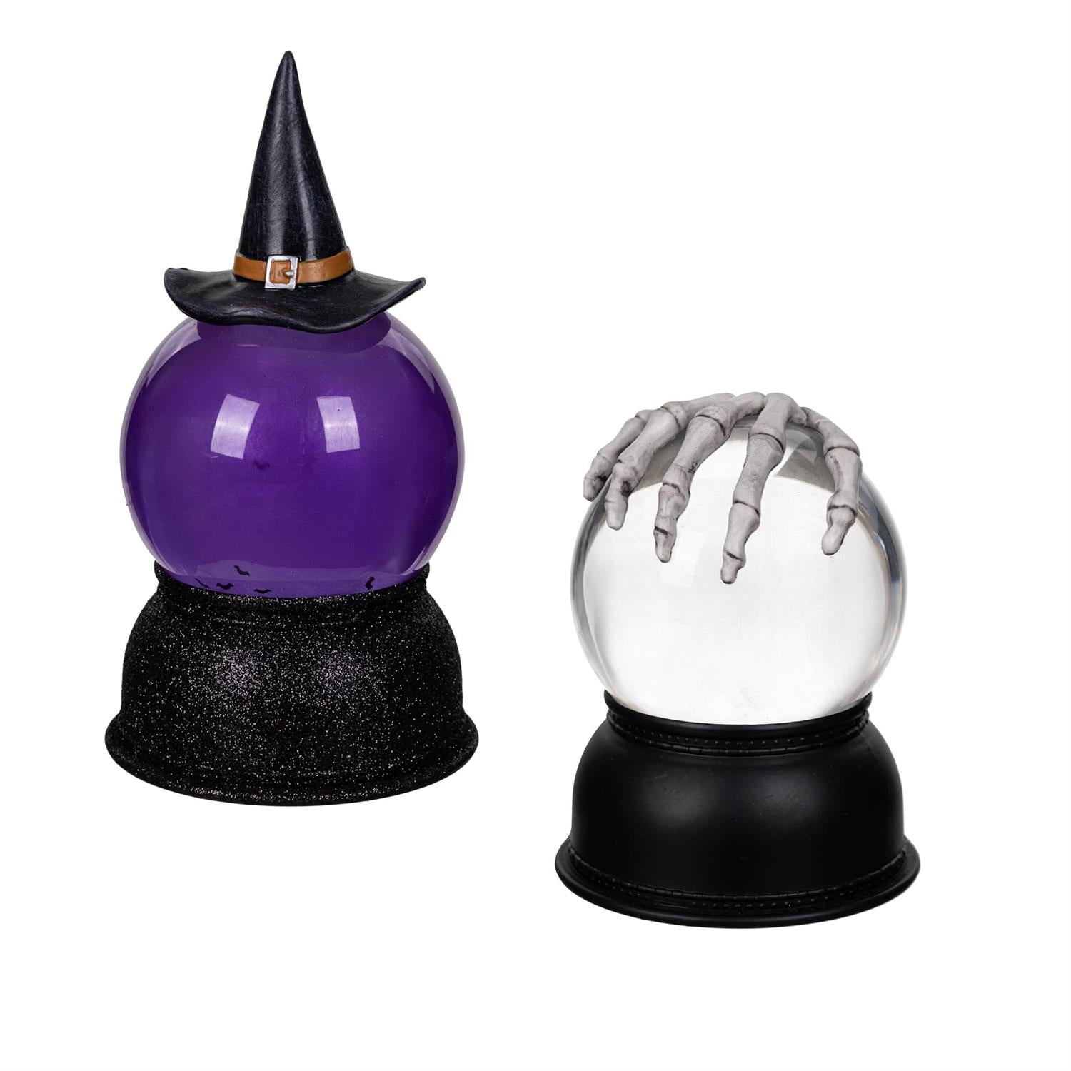 Two Halloween-themed snow globes lanterns with a purple sphere and witch hat, and a clear sphere with a skeleton hand, on black bases.
