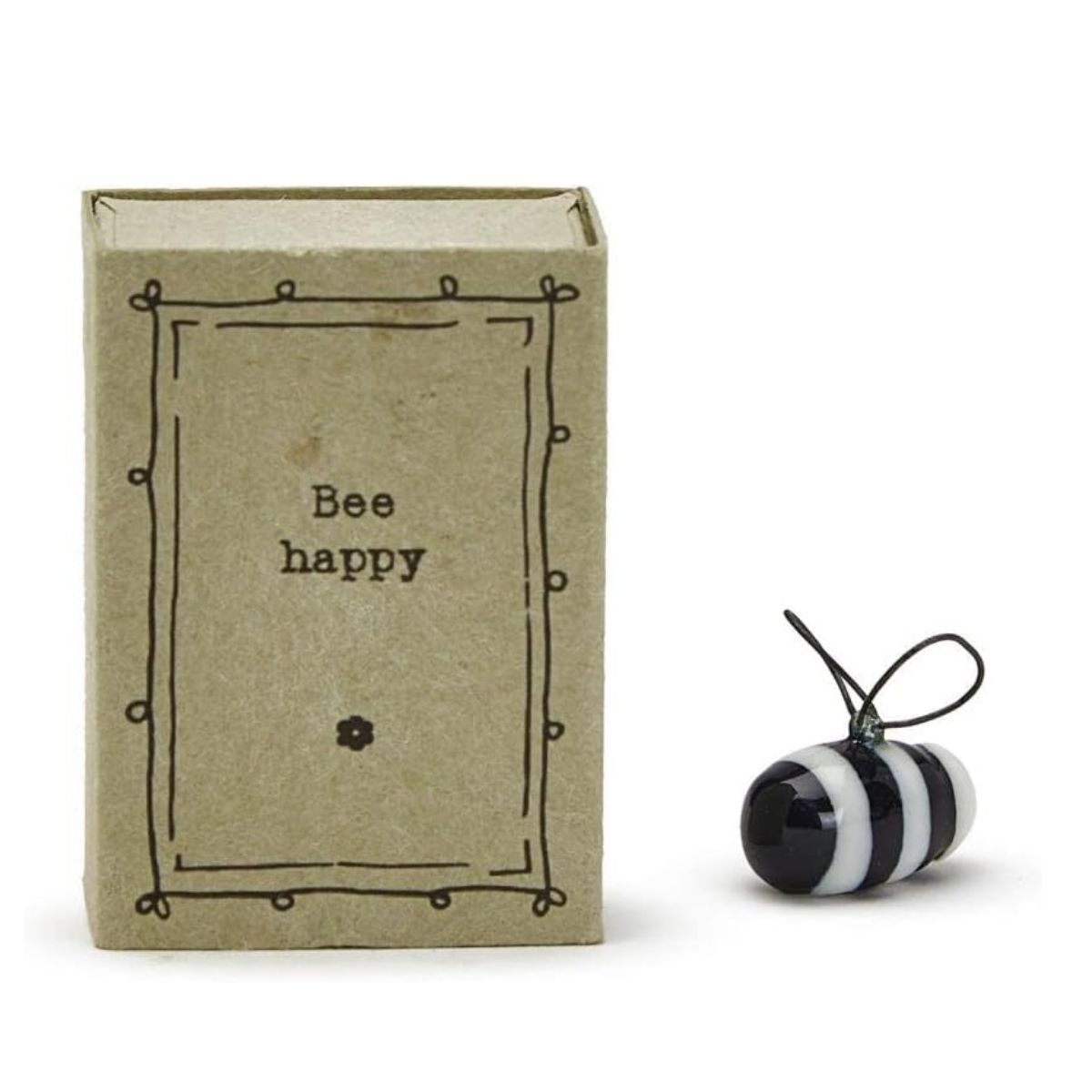 A porcelain bee figurine inside a cardboard matchbox with the text 'Bee happy' on the front.