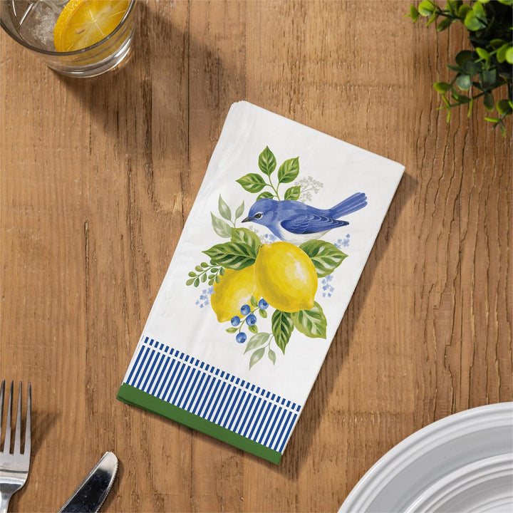 Decorative napkin with bird and lemon design on a wooden table.