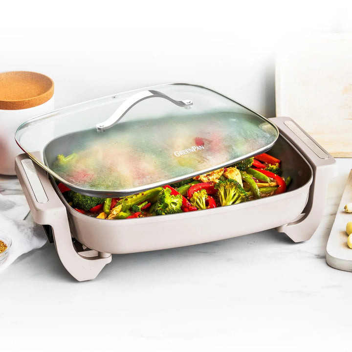 Electric frying pan with vegetables on a white surface