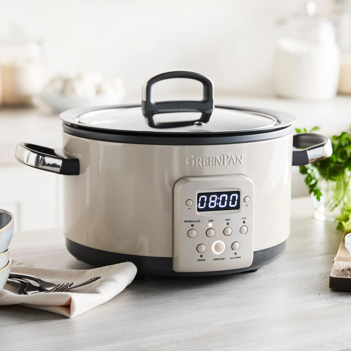 White slow cooker with digital display on a kitchen counter, featuring the GreenPan brand.