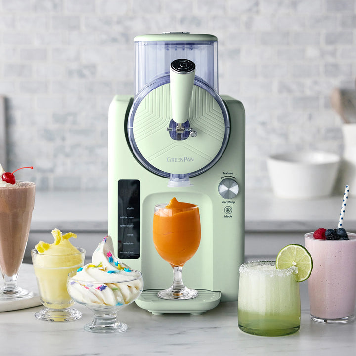 Green smoothie maker with various smoothies and desserts on a countertop.