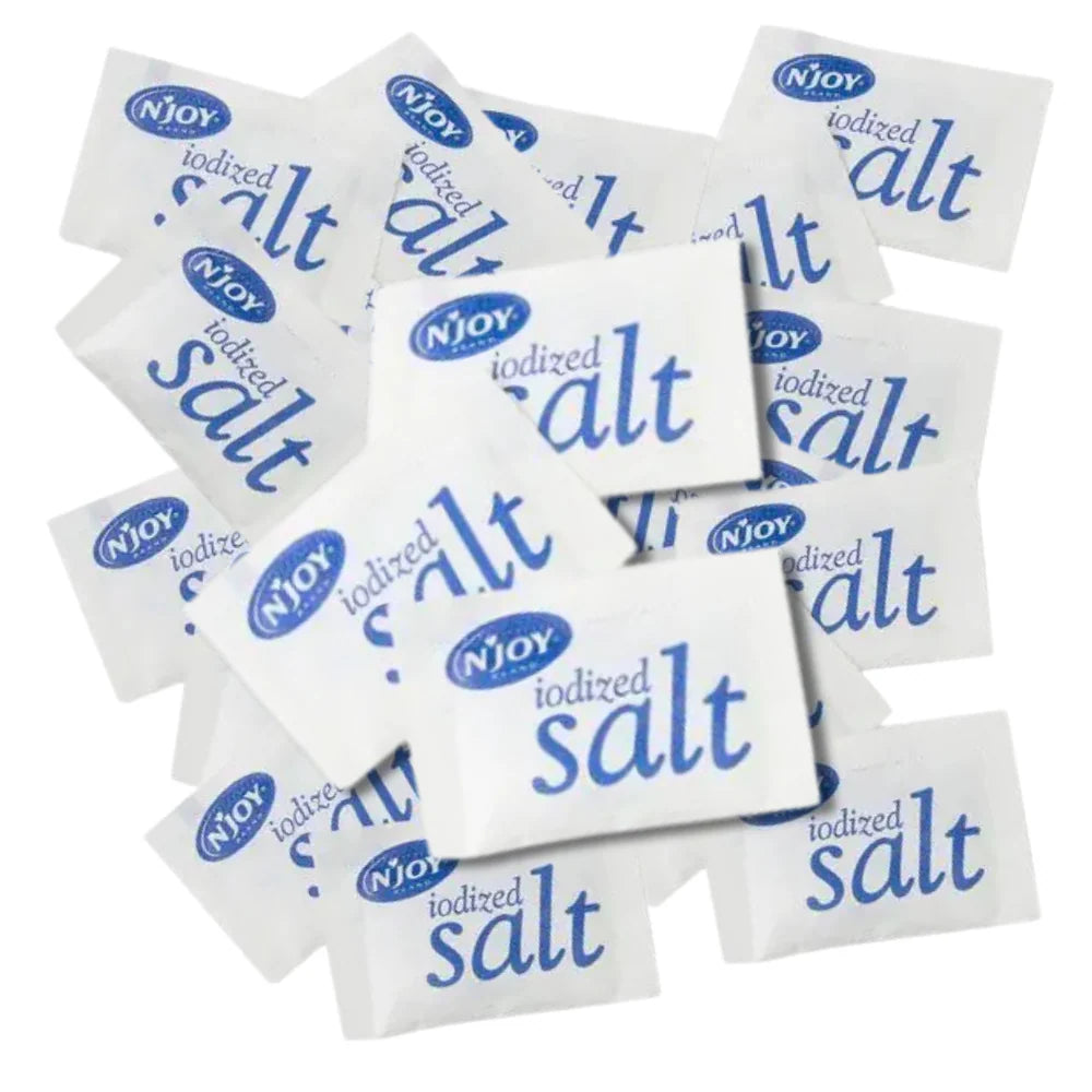 Multiple packets of N'Joy iodized salt on a white background